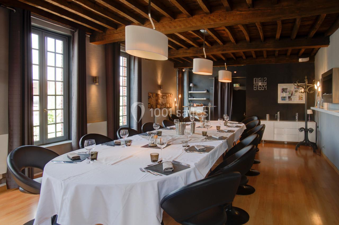SALON PICASSO - 20 PERSONNES - Repas de famille ou séminaire  Salle à manger élégante avec une grande table dressée, chaises noires, plafond en bois et lumière naturelle.