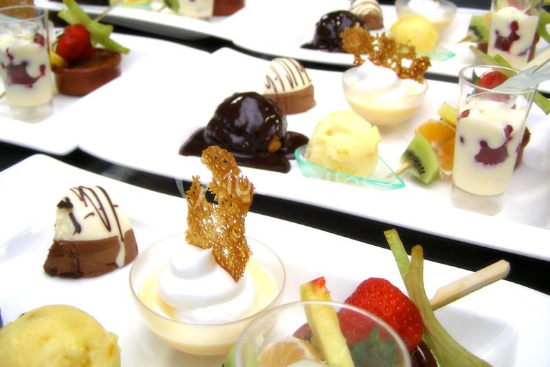 Assortiment de desserts variés présentés sur des assiettes blanches, incluant fruits, mousses et pâtisseries.