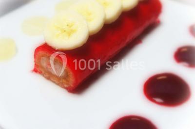 Miniature Traiteur Forest-sur-Marque (Nord) - Auberge du Tilleul #26 Dessert roulé recouvert de glaçage rouge, garni de rondelles de banane, avec des touches de coulis sur l'assiette blanche.