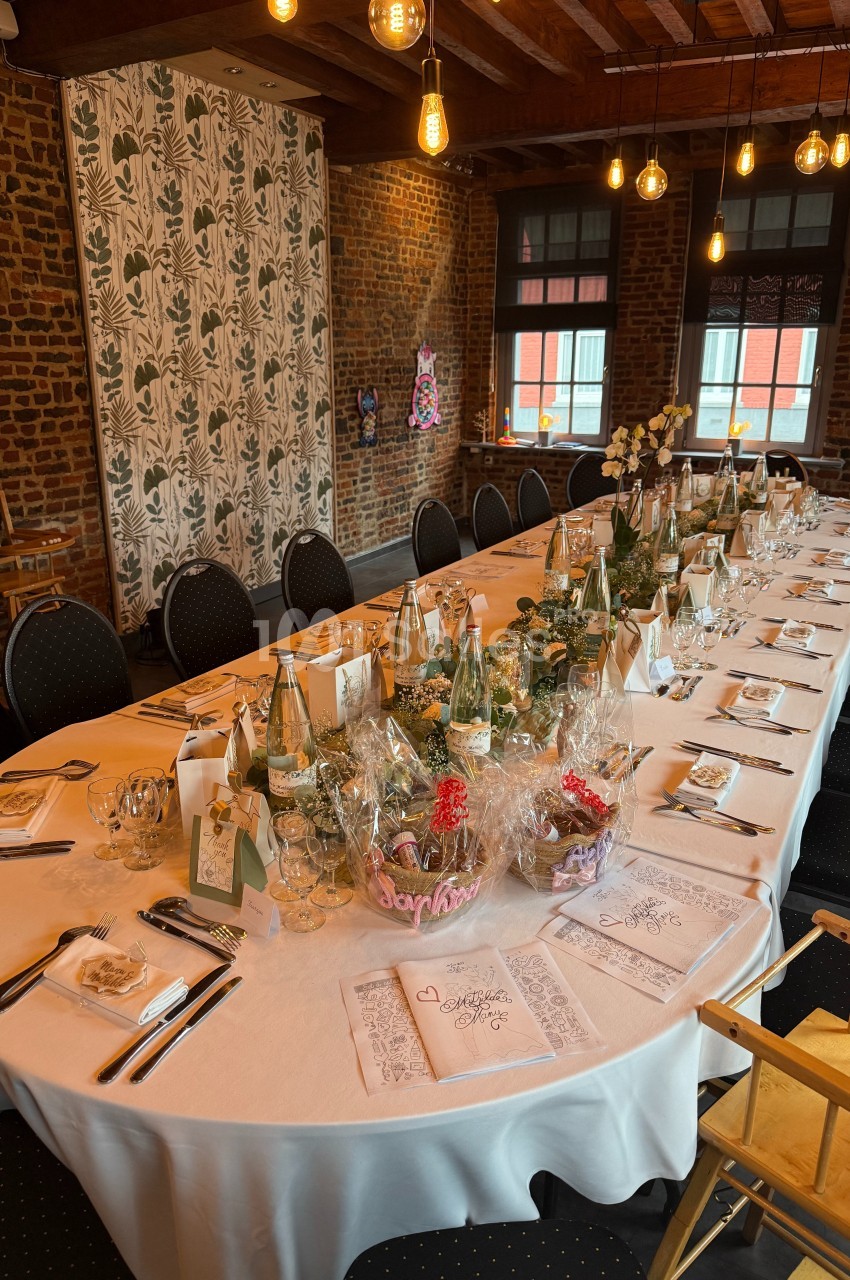 Table dressée pour un repas festif dans une salle en briques, décorée de lumières suspendues et de détails élégants.
