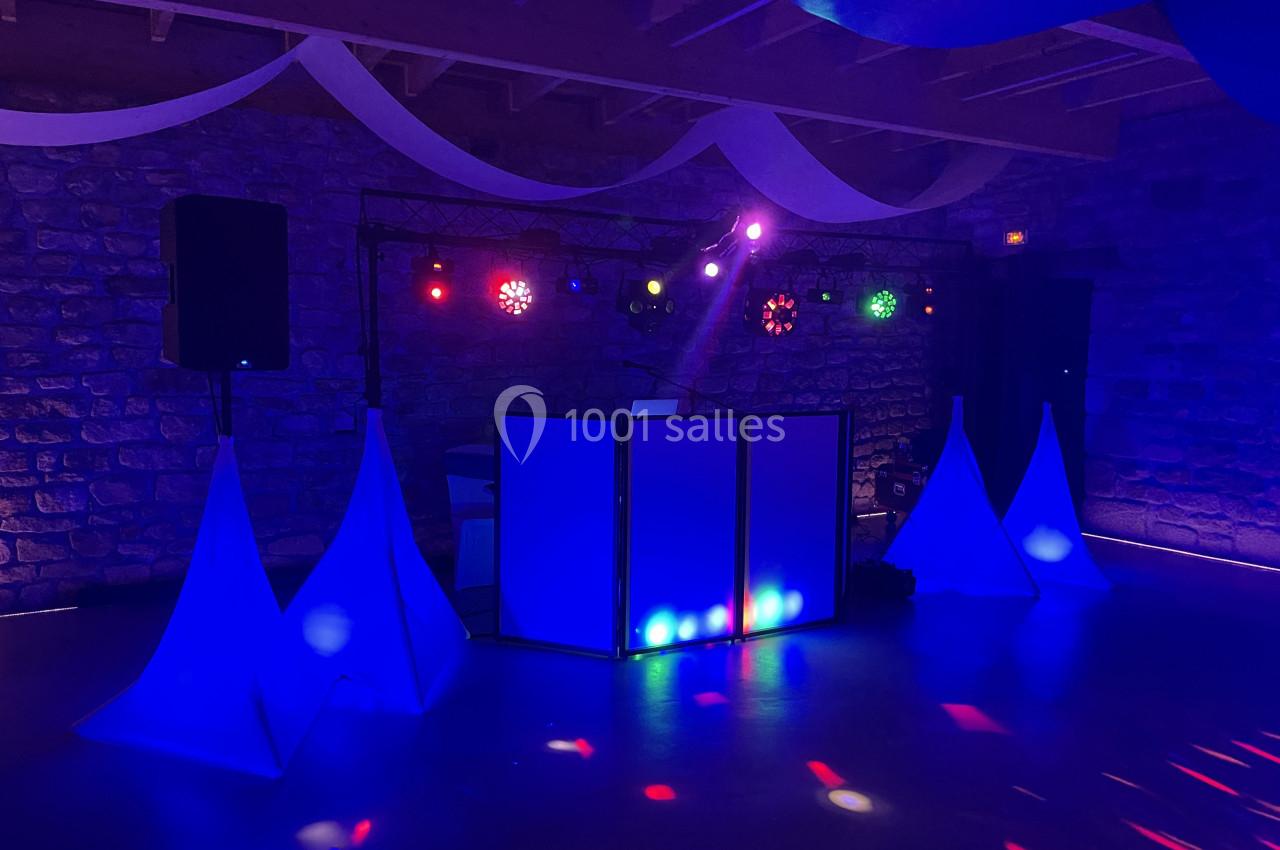 Installation de matériel de sonorisation et éclairage coloré dans une salle en pierre avec décorations suspendues.