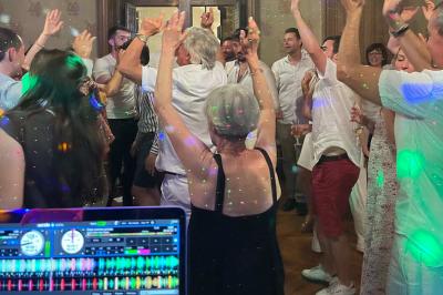 Miniature DJ Spézet (Finistère) - Anime dj Thony #28 Un couple danse sous des lumières violettes dans une salle sombre, vu depuis une table de mixage de DJ.