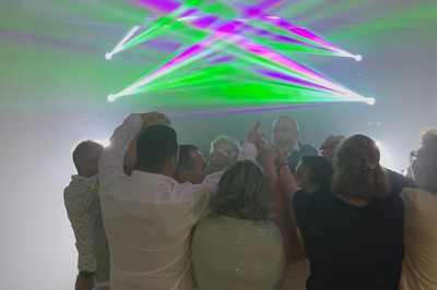 Un couple pose près d'une table décorée de fleurs et d'une pyramide de coupes de champagne dans une salle éclairée.