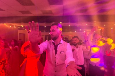 Un couple pose près d'une table décorée de fleurs et d'une pyramide de coupes de champagne dans une salle éclairée.