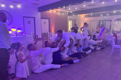 Un couple pose près d'une table décorée de fleurs et d'une pyramide de coupes de champagne dans une salle éclairée.