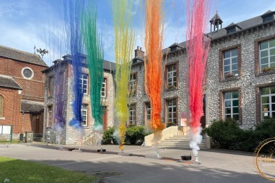 Un couple pose près d'une table décorée de fleurs et d'une pyramide de coupes de champagne dans une salle éclairée.