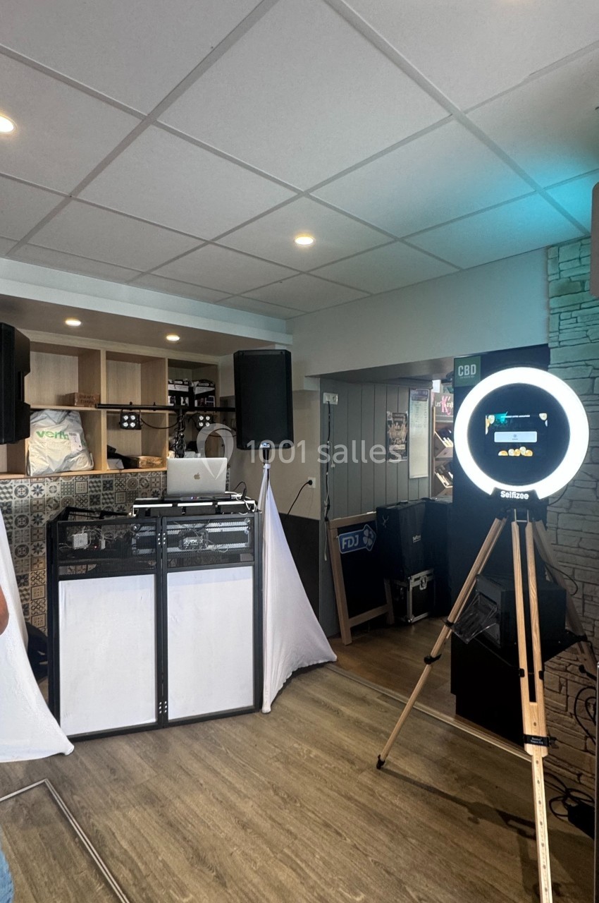 Poste de DJ avec platines, enceintes et éclairage, accompagné d'un photobooth avec anneau lumineux dans un espace intérieur.