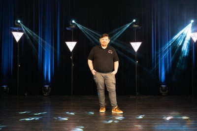 Installation de matériel de son et lumière dans une salle de réception lumineuse avec tables dressées.