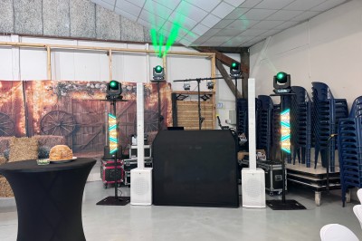 Installation de matériel de son et lumière dans une salle de réception lumineuse avec tables dressées.