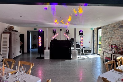 Installation de matériel de son et lumière dans une salle de réception lumineuse avec tables dressées.