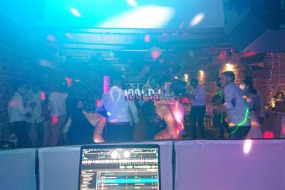 Personnes dansant sous des lumières colorées et des effets de fumée dans une ambiance festive.