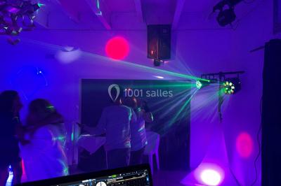 Personnes dansant sous des lumières colorées et des effets de fumée dans une ambiance festive.