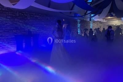 Personnes dansant sous des lumières colorées et des effets de fumée dans une ambiance festive.