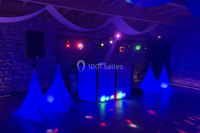 Personnes dansant sous des lumières colorées et des effets de fumée dans une ambiance festive.