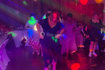 Personnes dansant sous des lumières colorées et des effets de fumée dans une ambiance festive.