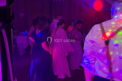 Personnes dansant sous des lumières colorées et des effets de fumée dans une ambiance festive.