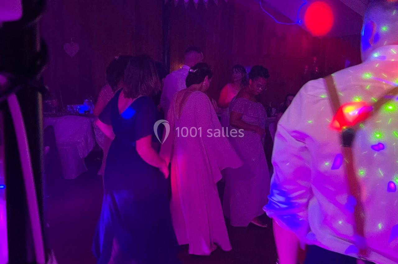 Des personnes dansent dans une salle faiblement éclairée avec des lumières colorées et une ambiance festive.