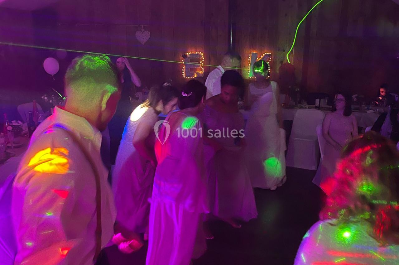 Personnes dansant sous des lumières colorées dans une salle décorée pour une fête ou un événement festif.