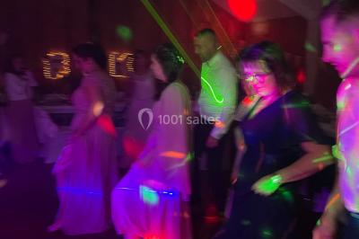 Personnes dansant sous des lumières colorées et des effets de fumée dans une ambiance festive.