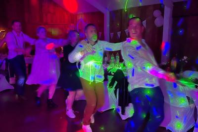 Personnes dansant sous des lumières colorées et des effets de fumée dans une ambiance festive.