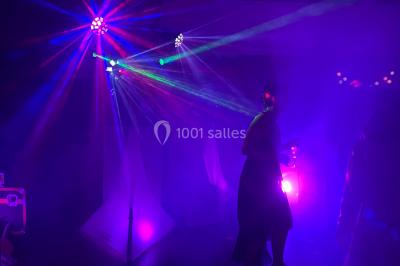 Personnes dansant sous des lumières colorées et des effets de fumée dans une ambiance festive.