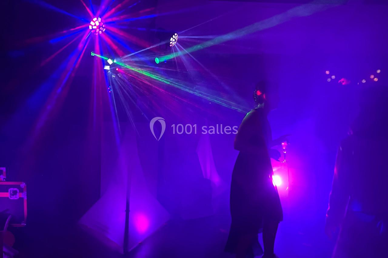 Personnes dansant sous des lumières colorées et des faisceaux lumineux dans une ambiance de soirée festive.