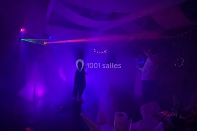 Personnes dansant sous des lumières colorées et des effets de fumée dans une ambiance festive.