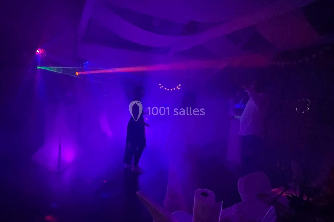 Personnes dansant sous des lumières colorées et des effets de fumée dans une ambiance festive.