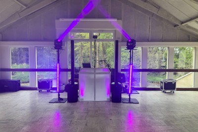 Salle en pierre avec plafond en poutres apparentes, éclairages décoratifs suspendus et équipement audio-visuel installé.