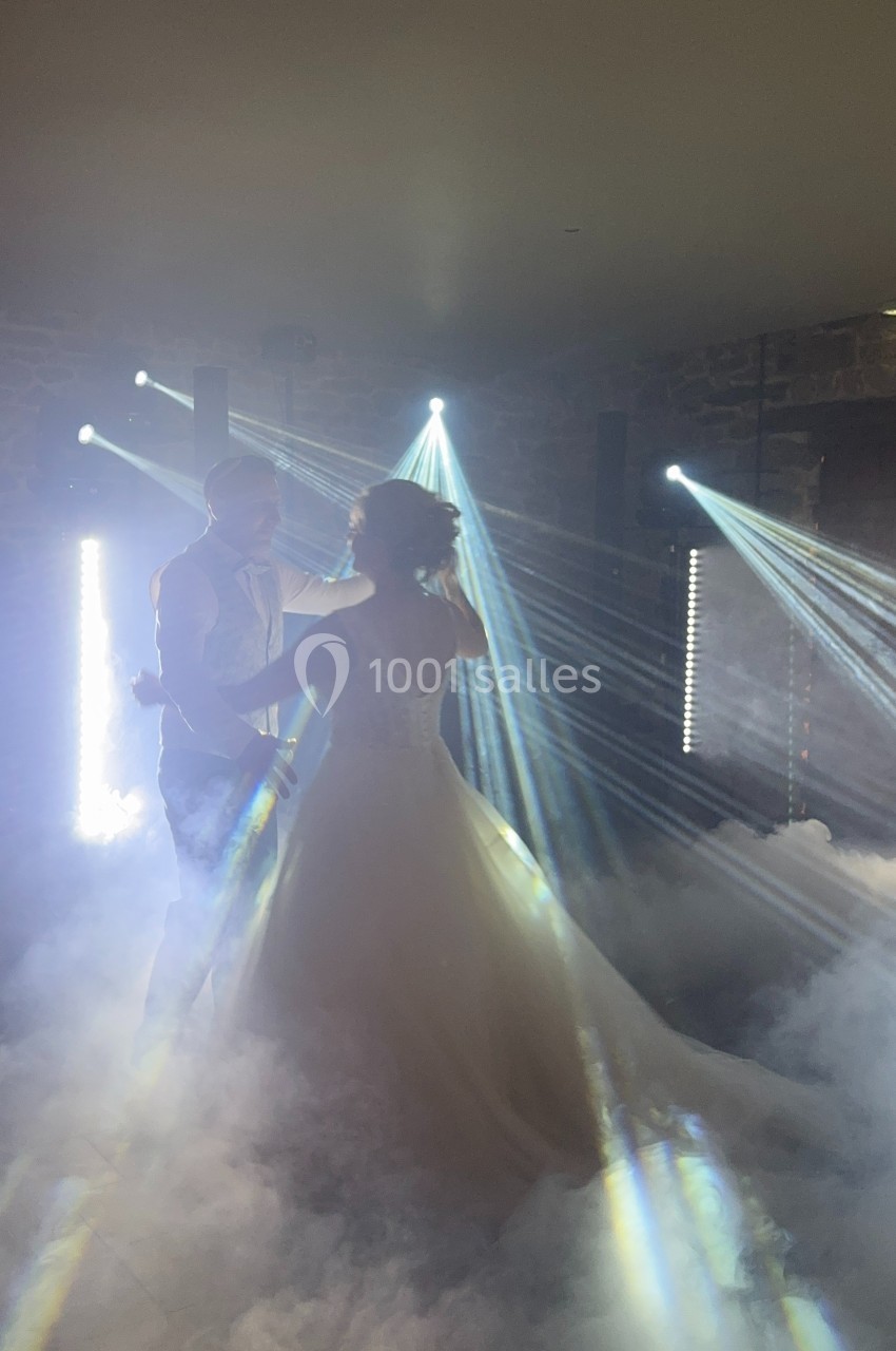 Un couple danse dans une ambiance lumineuse avec des faisceaux lumineux et de la fumée au sol.