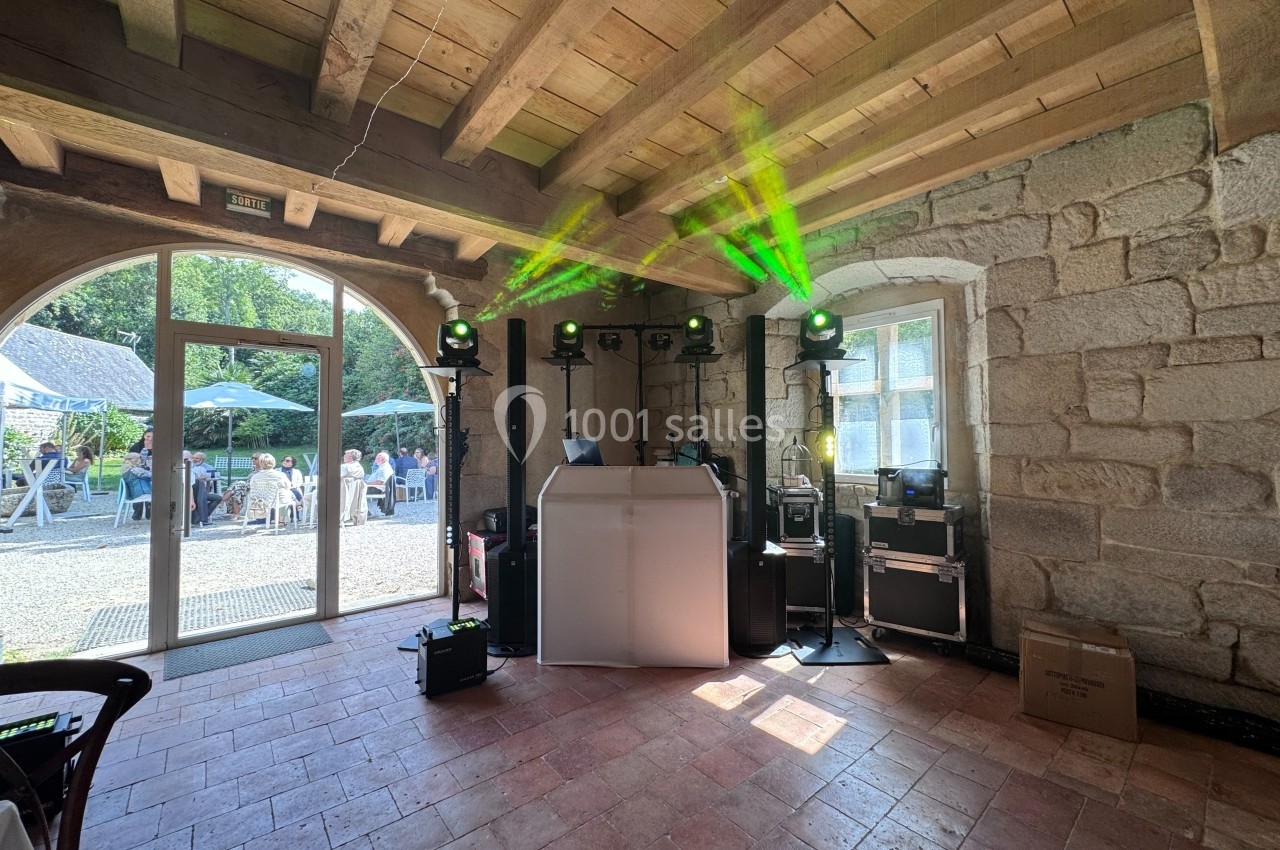 Installation de matériel de sonorisation et éclairage dans une salle en pierre avec vue sur une terrasse extérieure.