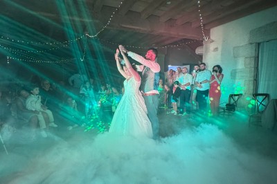 Salle en pierre avec plafond en poutres apparentes, éclairages décoratifs suspendus et équipement audio-visuel installé.