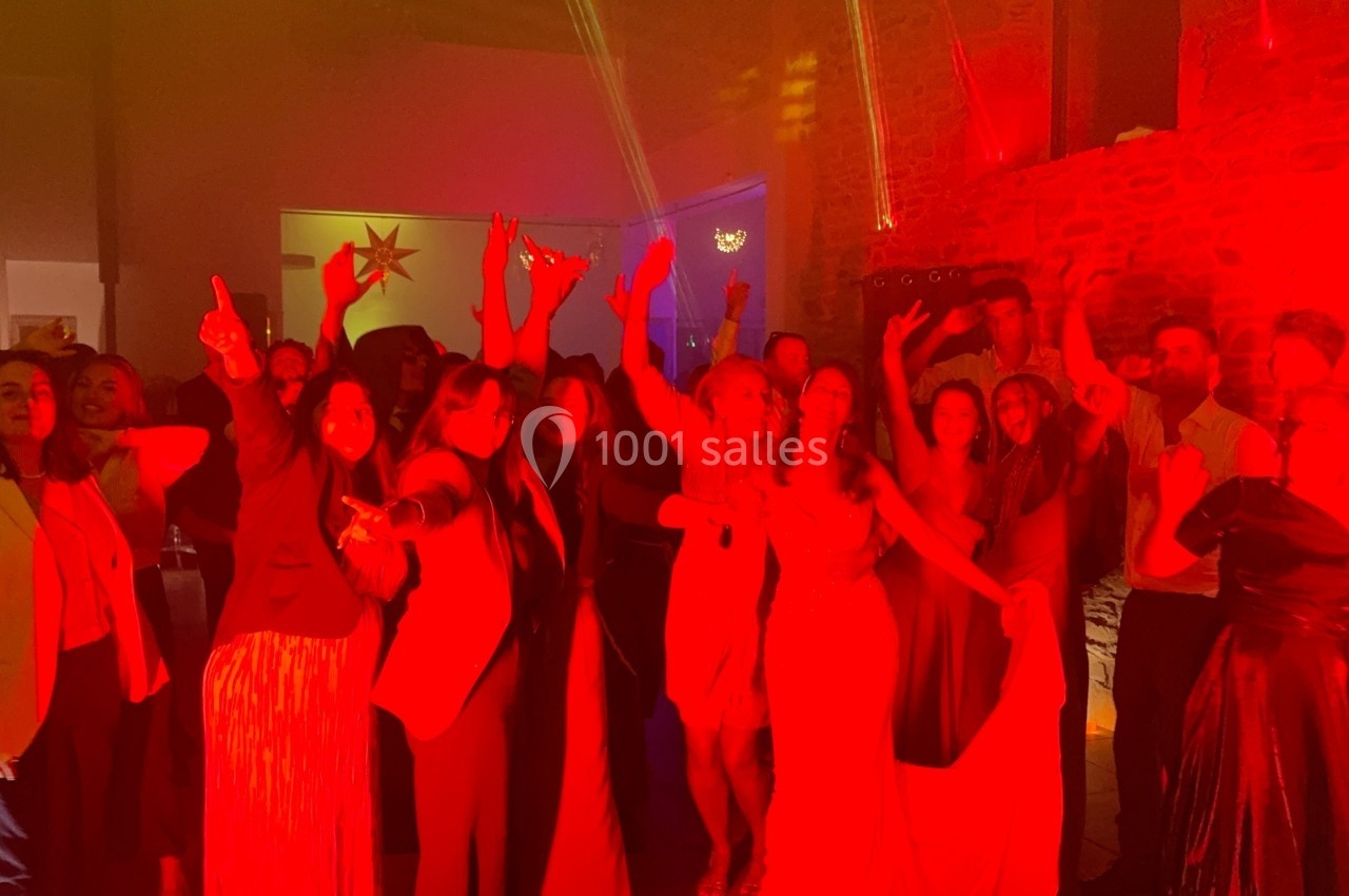 Groupe de personnes dansant et posant sous un éclairage rouge dans une salle avec murs en pierre.