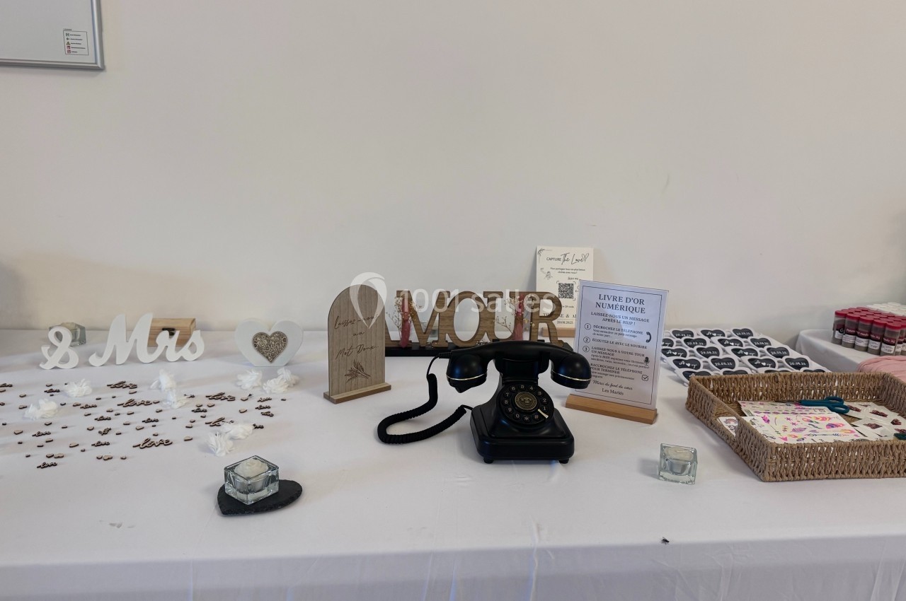 Table décorative avec un téléphone vintage, des accessoires de mariage et des boîtes de souvenirs sur une nappe blanche.