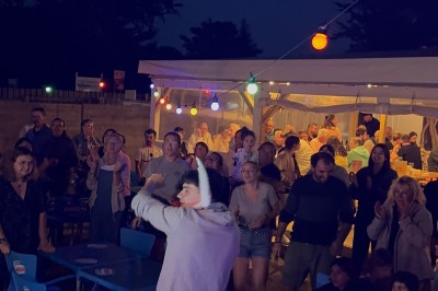 Salle en pierre avec plafond en poutres apparentes, éclairages décoratifs suspendus et équipement audio-visuel installé.