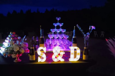 Salle en pierre avec plafond en poutres apparentes, éclairages décoratifs suspendus et équipement audio-visuel installé.