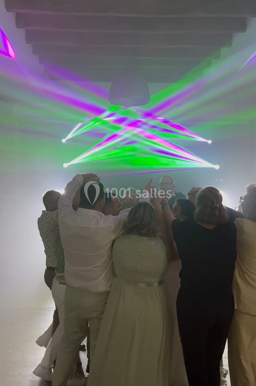 Groupe de personnes dansant sous des lumières colorées dans une salle sombre avec un plafond en bois.