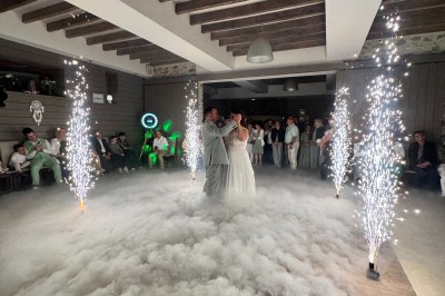 Salle en pierre avec plafond en poutres apparentes, éclairages décoratifs suspendus et équipement audio-visuel installé.