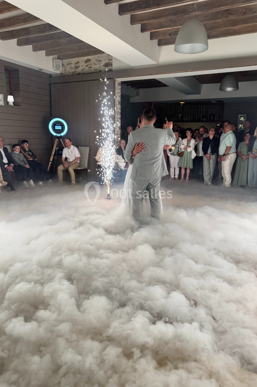 Un couple danse au milieu d'une piste entourée de fumée et d'étincelles, sous le regard des invités.