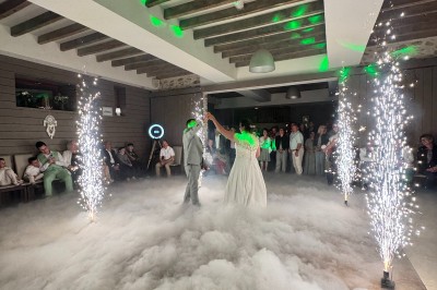 Salle en pierre avec plafond en poutres apparentes, éclairages décoratifs suspendus et équipement audio-visuel installé.
