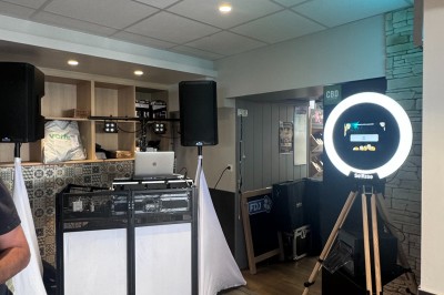 Salle en pierre avec plafond en poutres apparentes, éclairages décoratifs suspendus et équipement audio-visuel installé.