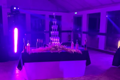 Salle en pierre avec plafond en poutres apparentes, éclairages décoratifs suspendus et équipement audio-visuel installé.