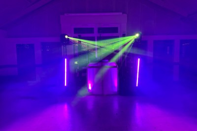 Salle en pierre avec plafond en poutres apparentes, éclairages décoratifs suspendus et équipement audio-visuel installé.