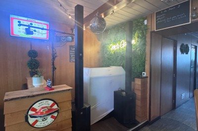 Salle en pierre avec plafond en poutres apparentes, éclairages décoratifs suspendus et équipement audio-visuel installé.