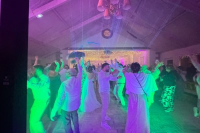 Salle en pierre avec plafond en poutres apparentes, éclairages décoratifs suspendus et équipement audio-visuel installé.