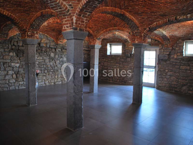 Location salle Ciney (Province de Namur) - Le Domaine d'Achêne #7 Salle voûtée en briques et pierres, éclairée par des fenêtres et une porte, avec des colonnes en pierre.
