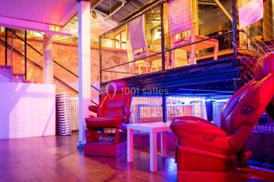 Escalier intérieur éclairé menant à un espace mezzanine, avec murs en pierre et plantes décoratives.