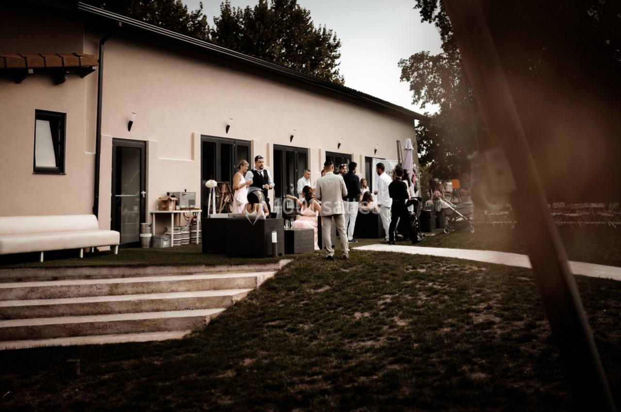 Groupe de personnes rassemblées devant un bâtiment moderne avec terrasse, en extérieur, par temps clair.