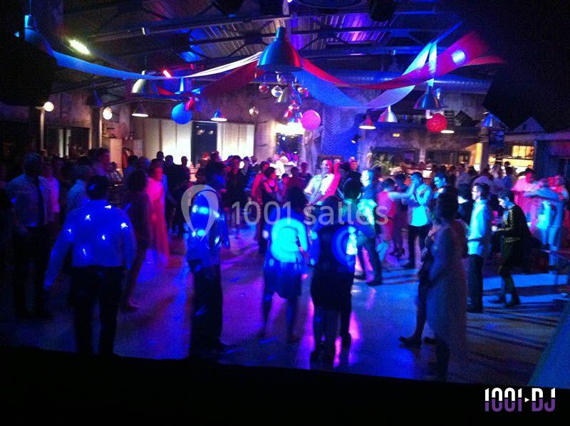 Des personnes dansent sous des lumières colorées dans une salle décorée pour une fête ou un événement.