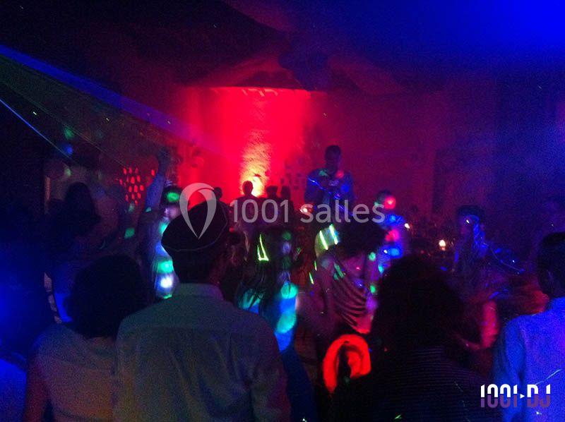 Personnes dansant dans une salle sombre éclairée par des lumières colorées et des effets lumineux.